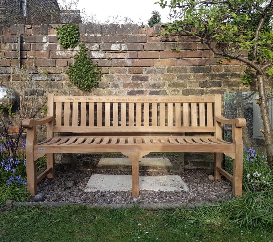 a garden bench memorial with engraving on the top rail